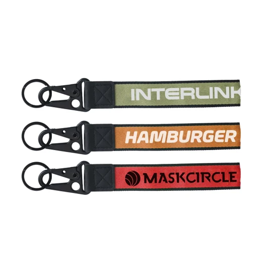 Three keyrings in green, orange, and red, featuring various designs and attached metal clasps. Each has a logo.