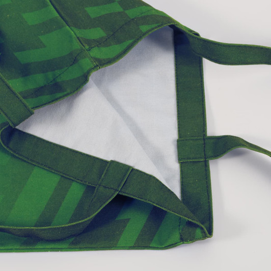 A green 220gsm sublimation canvas tote bag with a patterned exterior and plain interior, featuring sturdy handles.