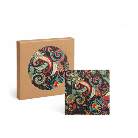 A square ceramic coaster featuring a colourful paisley design, displayed alongside its brown packaging.