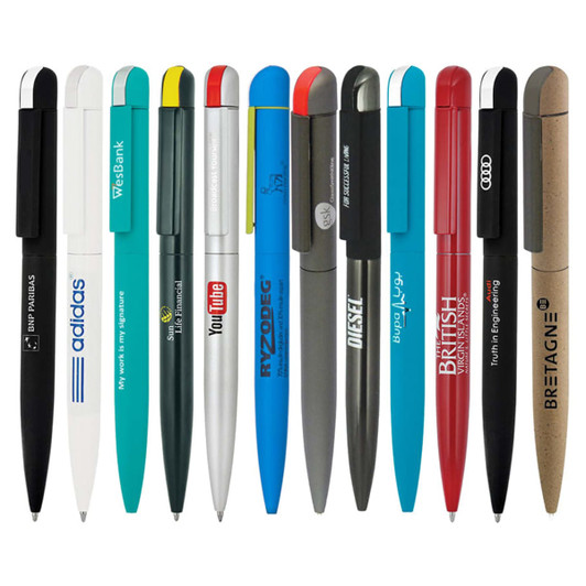 A collection of metal ballpoint pens in various colours, featuring logos and brand names, arranged in a line.