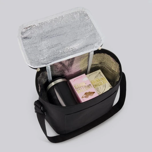 A black insulated bag containing a drink bottle, snacks, and a box of chocolates, with a silver liner.