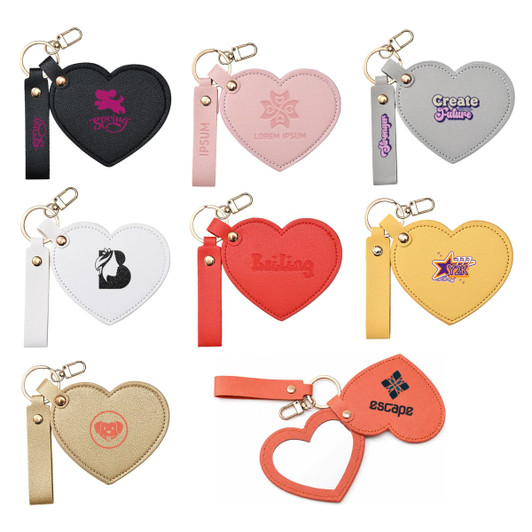 A collection of heart-shaped compact mirrors in various colours, featuring keychains and distinct logos.