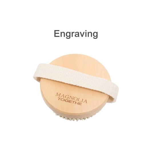 A round exfoliating brush with soft massage nodules, featuring a wooden top and a fabric strap. Includes branding.