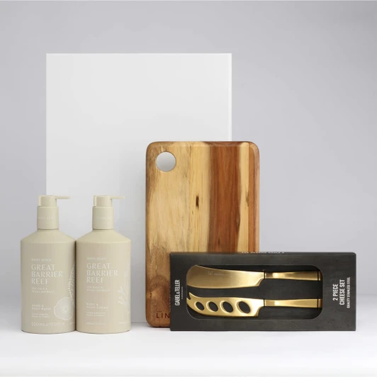 A wooden chopping board, two beige pump bottles, and a boxed set of gold-coloured utensils.