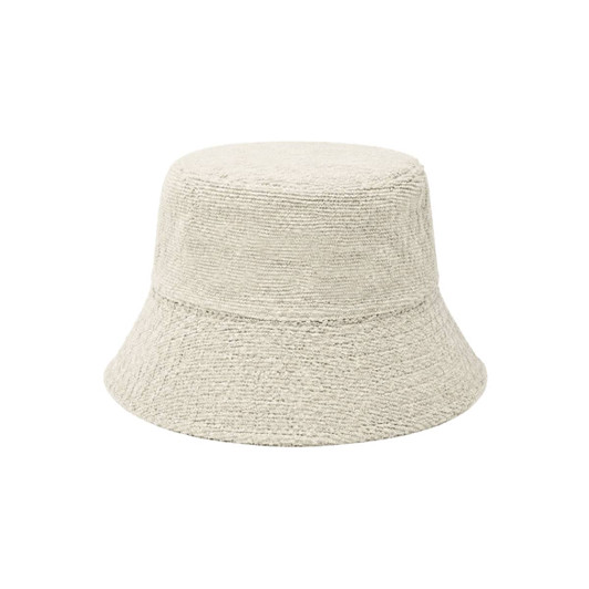 A dual-material reversible bucket hat in a light beige colour with a textured finish. It features a logo.
