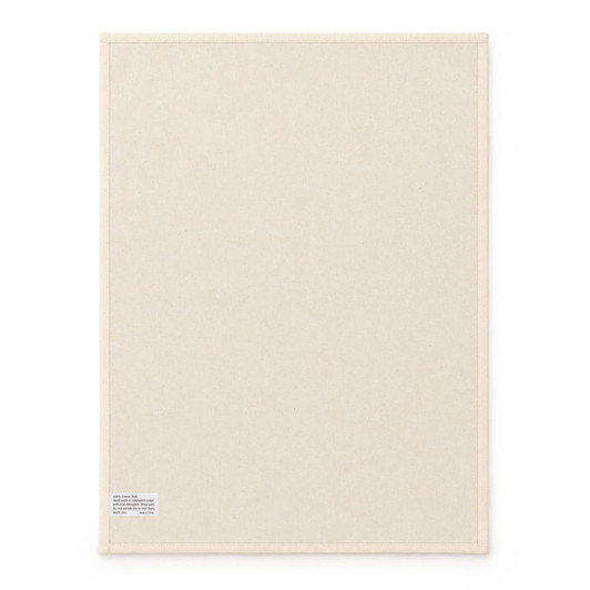 A large cream cotton tea towel featuring a plain design and a small label in one corner.