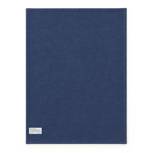 A large navy blue cotton tea towel with stitched edges and a small branding label at the bottom.