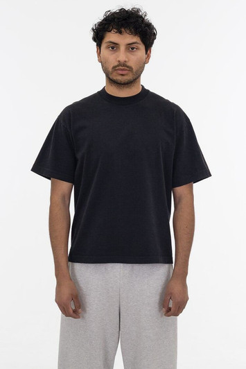 A black short sleeve garment dye t-shirt worn by a person, paired with light grey pants, featuring a logo.