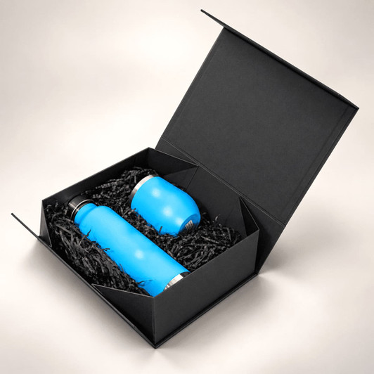 A black magnetic gift box containing a blue drink bottle and a blue cup, surrounded by black filler material.