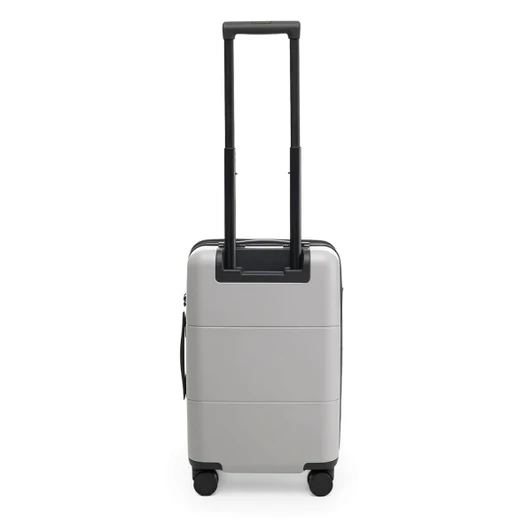 A silver carry-on suitcase with a retractable handle and wheels, featuring a simple design and a logo.