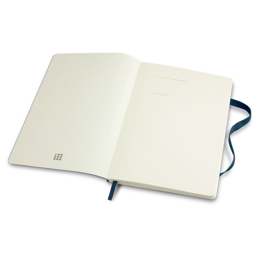 A large Moleskine classic soft cover notebook with a plain interior and a blue ribbon bookmark.