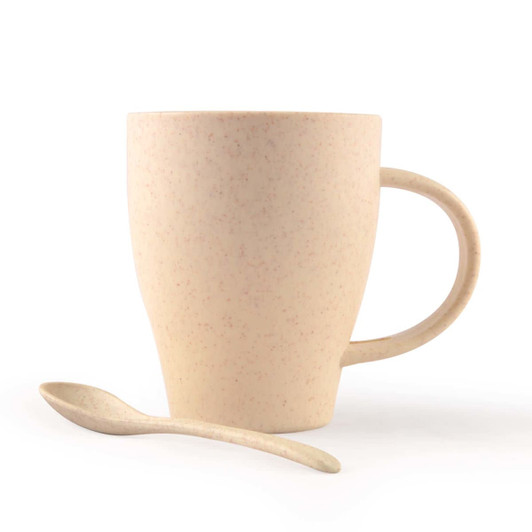 A drink cup in light beige with a handle and a matching spoon, made of wheat fibre material.