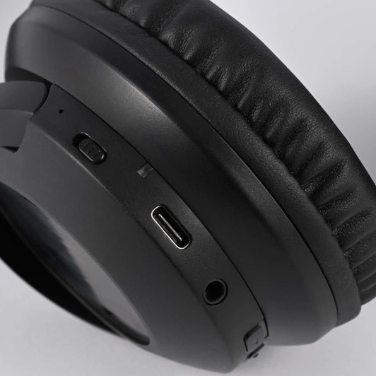 A close-up of black headphones featuring buttons and a USB-C port. There is a logo on the side.