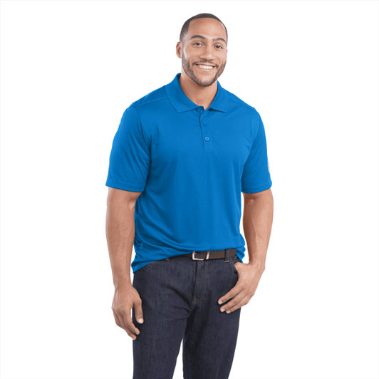 A men's short sleeve polo shirt in bright blue, featuring a collar and a logo. Model is smiling while wearing it.