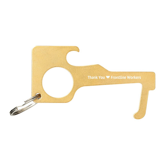 A gold keychain tool shaped to avoid contact with surfaces, featuring a circular hole and a decorative design.