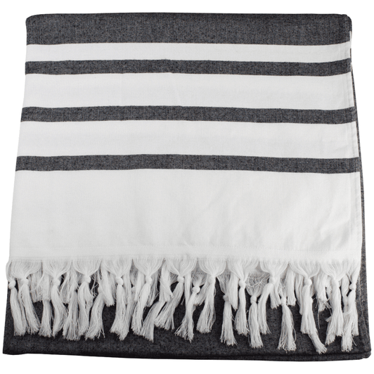 A Turkish beach towel displaying alternating dark grey and white stripes, featuring a fringed edge.