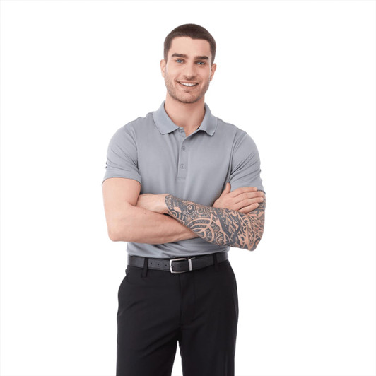 A men's short sleeve polo shirt in light grey, modelled by a smiling man with tattoos, wearing black pants and a belt.