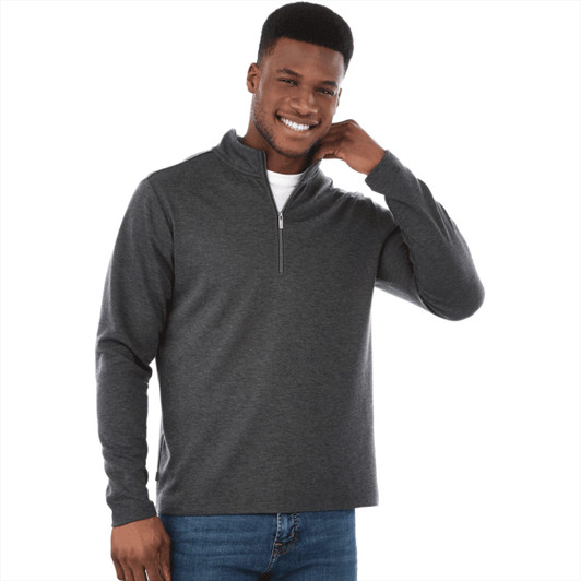 A man wearing a dark grey knit quarter zip jumper, smiling and adjusting the collar. The jumper features a subtle logo.