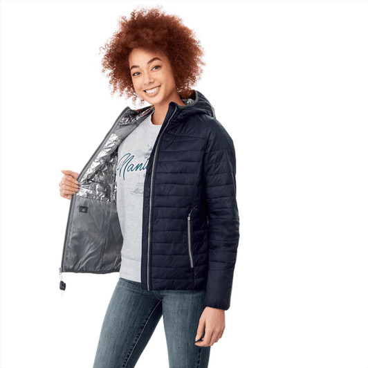 A woman wearing a navy packable insulated jacket, smiling, with an opened front showcasing a silver lining.