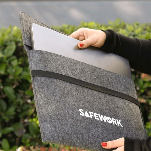 A grey felt laptop sleeve is being held, with a laptop partially inserted. It has a logo on the front.
