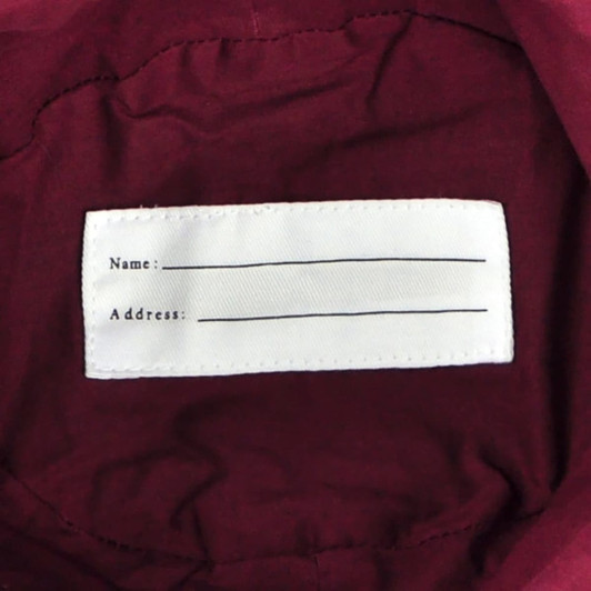 A maroon hat interior featuring a blank label for name and address. The hat has a simple, unembellished design.