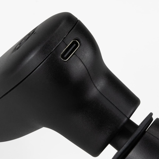 A compact handheld massager in sleek black, featuring a charging port and ergonomic design.