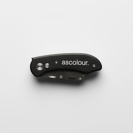 A black ASC Utility Knife with a sleek design, featuring a foldable blade and a logo on the surface.