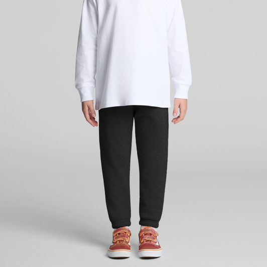 Track pants in dark grey, paired with a long-sleeve white top and red-orange shoes, featuring a logo.