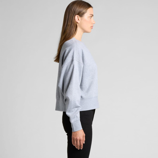 A grey oversized crew jumper features long sleeves and a cropped silhouette, paired with black trousers.
