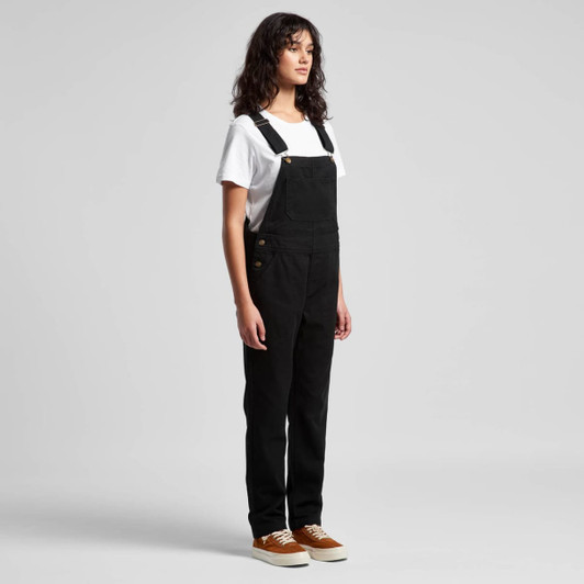 Black canvas overalls featured on a model, paired with a white t-shirt and brown shoes. The overalls have a logo detail.