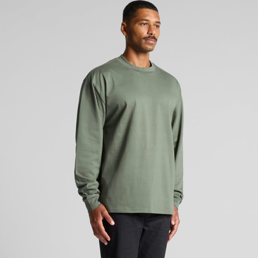 A long-sleeved tee in olive green, featuring a minimalist design and a logo. Model standing against a neutral background.