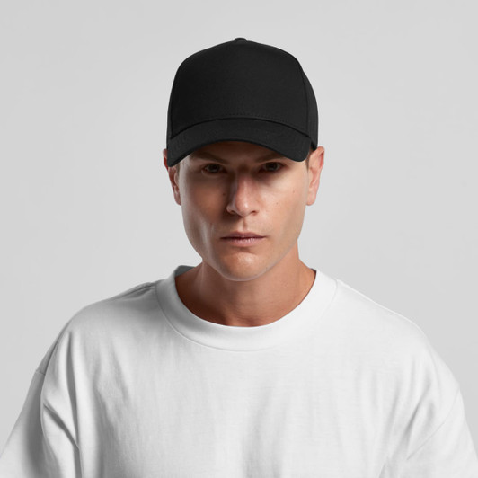 A black cap with a structured design and a logo, worn by a model in a white t-shirt.