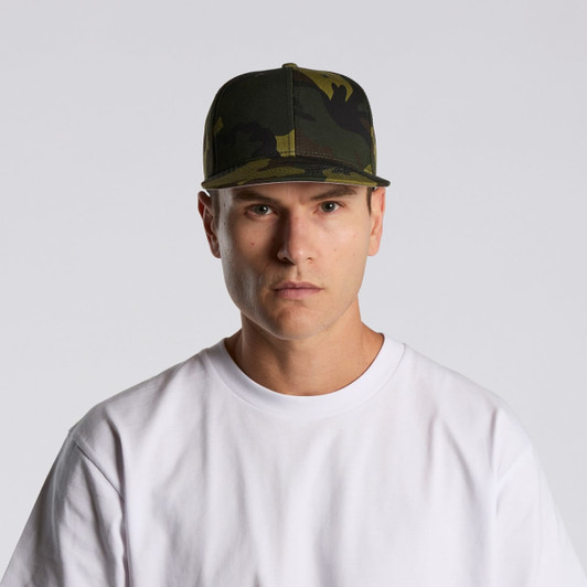 A camouflage cap featuring various shades of green, worn by a model in a plain white t-shirt.