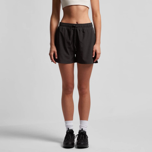 A pair of black sports shorts with an elastic waistband, modelled by a person standing.