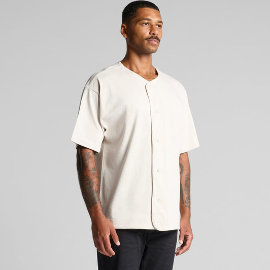 A heavy baseball jersey in cream colour, featuring a button front and short sleeves, worn by a male model.