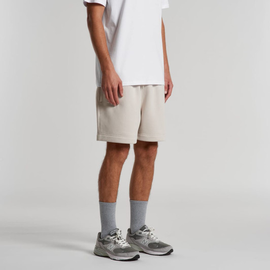 Relax Track Shorts in light beige, styled with a white shirt and grey sneakers. The shorts feature a logo.