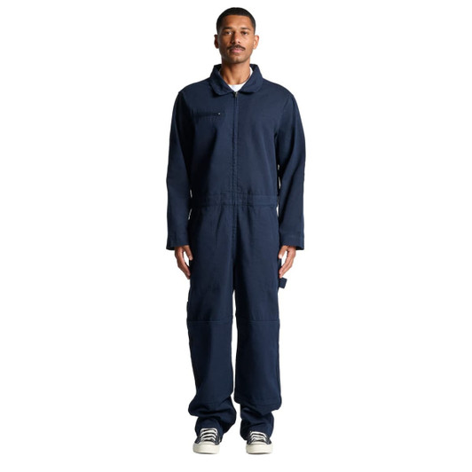 A male model wearing navy blue canvas coveralls, featuring a collar and long sleeves. The outfit has a logo.