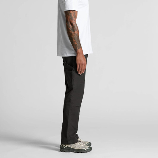 Cargo pants in black, featuring multiple pockets, styled with a plain white t-shirt and grey shoes, side view.
