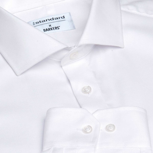 A white button-up shirt with a collar, featuring a logo tag and multiple white buttons.