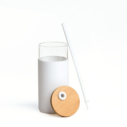 A drink bottle made of clear glass with a white silicone sleeve, a bamboo lid, and a white straw.