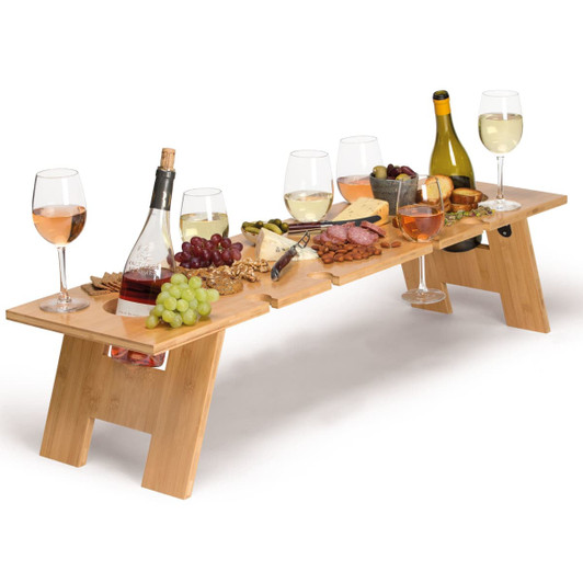 A wooden tabletop in natural colour, featuring wine bottles, glasses, and an array of fruits and cheeses.