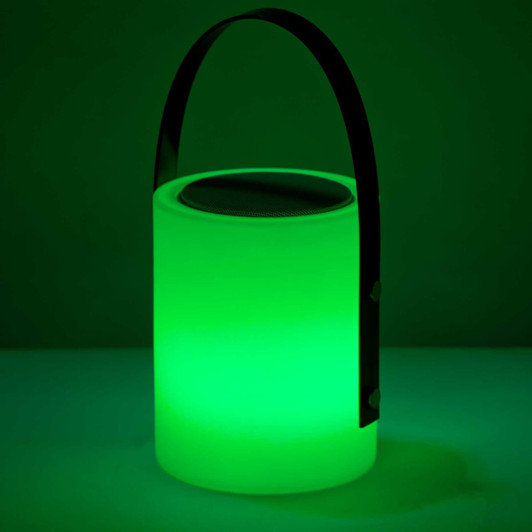 A green, cylindrical speaker lamp with a black handle and a metallic top, emitting glowing light.