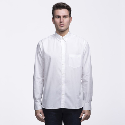A white button-up shirt featuring a chest pocket, styled with a collar. The model is standing against a plain background.