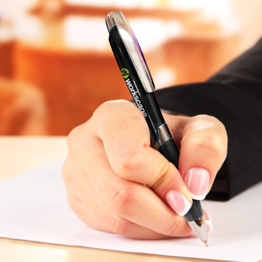 A black plastic pen being held, with a hand writing on a sheet of paper. The pen features a logo.