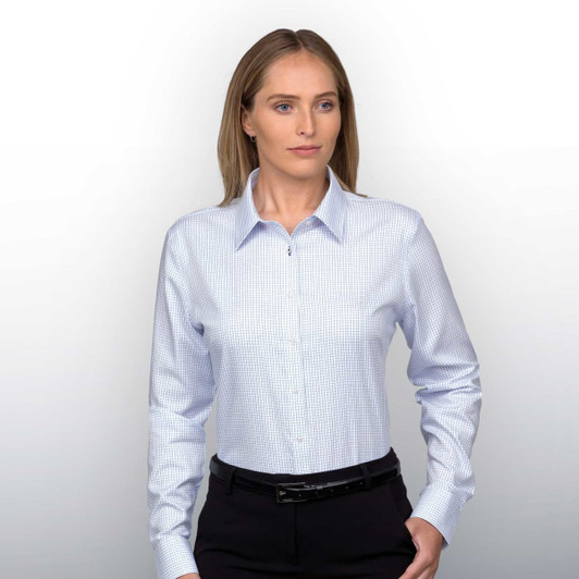 A woman wearing a light blue check button-up shirt with long sleeves, paired with black trousers.