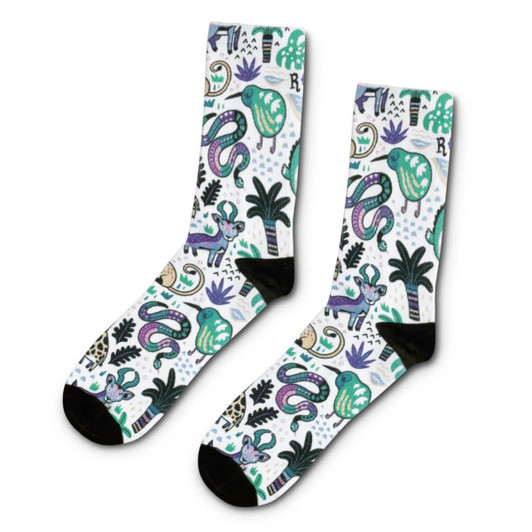 A pair of crew socks featuring a vibrant design with green, purple, and black motifs, including animals and plants.