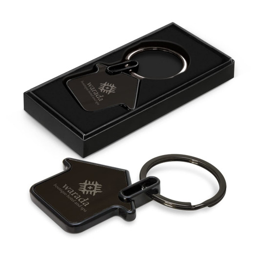 A black house-shaped key ring in a gift box, featuring a logo on the surface.