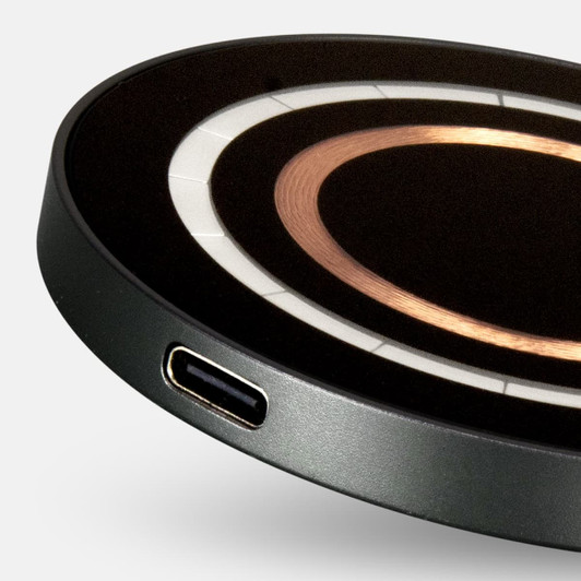 A round, black wireless charger with a copper centre and a USB-C port. It has a sleek, minimalist design.