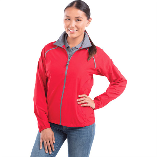 A woman is wearing a red packable rain jacket with a grey collar and a zippered front. The jacket has a logo.