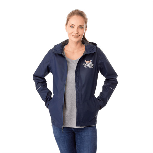 A women's rain jacket in navy blue with a hood and a logo on the chest, paired with a grey top and denim jeans.